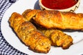 Sausages baked in dough sprinkled with salt and poppy seeds and bowl with tomatoes sauce in a rustic composition. Sausages rolls, Royalty Free Stock Photo