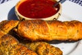 Sausages baked in dough sprinkled with salt and poppy seeds and bowl with tomatoes sauce in a rustic composition. Sausages rolls, Royalty Free Stock Photo