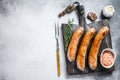 Sausages barbecue fried with spices and herbs on a wooden cutting board. Top view. White background. Copy space