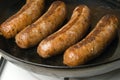Sausages in a black frying pan with gas stove