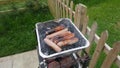 Sausages and burgers cooking on a disposable BBQ Barbeque in s garden Royalty Free Stock Photo