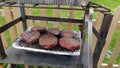 Sausages and burgers cooking on a disposable BBQ Barbeque in s garden Royalty Free Stock Photo