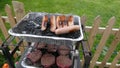 Sausages and burgers cooking on a disposable BBQ Barbeque in s garden Royalty Free Stock Photo