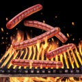 Sausages falling on the burning grill grate and tongues of fire flame