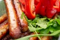 Sausages are fried in the grill and arugula, red bell pepper
