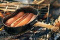 Sausages fries at bonfire coals. cooking at campfire. Trekking or hiking cuisine Royalty Free Stock Photo