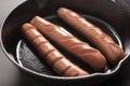 Sausages in frying pan over dark background isolated. Cooking breakfast hot dogs Royalty Free Stock Photo