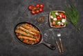 Sausages on the grill pan on the wooden background. Top view. Frying pan with fried sausage, vegetables and fork and knife on a