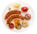 Sausages grilled with vegetables and sauce on the plate. Isolate