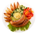 Sausages grilled with vegetables and sauce on the plate. Isolate