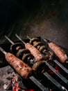 Sausages and mushrooms on skewers over hot coals of a grill Royalty Free Stock Photo