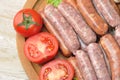 Sausages in a natural shell on a tray with tomatoes Royalty Free Stock Photo