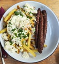 Sausages with poached eggs and fried potatoes with cheese