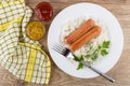 Sausages with rice, bowls with mustard and ketchup, napkin