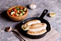 Sausages in rustic pan with onion. Frying pan with fried sausage
