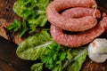 sausages in rustic style.Raw homemade sausage rings, fresh parsley, on lettuce leaves on a wooden board. appetizing meat Royalty Free Stock Photo