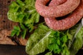 sausages in rustic style.Raw sausage rings, fresh parsley, on lettuce leaves on a wooden board. appetizing meat products Royalty Free Stock Photo