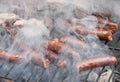 Sausages on a smoking grill, close-up. Sausage BBQ on wood ember, smoking. Barbecue, smoke background