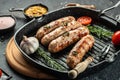 Sausages with spices in a pan with rosemary herbs on the grill pan. banner, menu, recipe place for text, top view Royalty Free Stock Photo