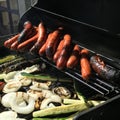 Sausages and vegetables cooking on grill in summer