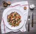 Sauteed beef with grilled vegetables on white plate with knife and fork on a napkin with spices on wooden rustic background top vi