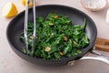 Sauteed garlic spinach in a pan with slices of crispy garlic