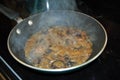 Sauteing mushrooms and onions in a frying pan with oil, seasoning, and steam