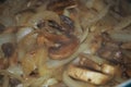 Sauteing mushrooms and onions in a frying pan with oil, seasoning, and steam