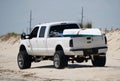 Savage Ditch, Delaware, U.S.A - July 4, 2023 - A white Ford truck with a kayak and surf fishing beach permit moving on the sand