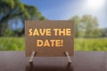 Save the date text on card on the table with sunny green park background Royalty Free Stock Photo