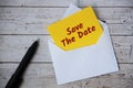 Save the date text on yellow notepad in an envelope with pen and wooden desk background. Reminder concept Royalty Free Stock Photo