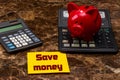 SAVE MONEY message card yellow next to a piggy bank on a calculator Royalty Free Stock Photo