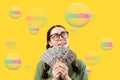 Save money. Pretty smiling caucasian young woman wearing eyeglasses holding fan of dollar currency and dreaming about Royalty Free Stock Photo