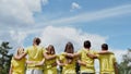 Save the nature. Group of young volunteers wearing uniform and rubber gloves hugging and looking at green forest in