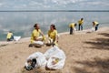 Save our planet. Group of young eco activists or volunteers in uniform cleaning together the beach from collecting