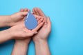 Save Water concept. Man and woman holding paper drop on light blue background, top view with space for text Royalty Free Stock Photo