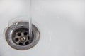 Save water A jet of water gets directly into the drain hole in a white sink or bathtub. Royalty Free Stock Photo