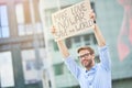 Save the world. Happy young male activist holding banner or poster over the head while protesting against war, standing