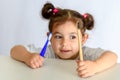 Little girl in white shirt holding bamboo toothbrush and plastic toothbrush.