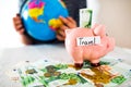 Saving concept. Piggy bank with an inscription travel. Woman holding a globe