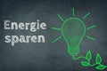 Saving energy, german language, chalkboard, drawing of a green light bulb Royalty Free Stock Photo
