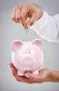 Saving every penny. Cropped image of a man putting money in a piggybank.