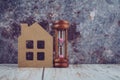 Home replica and hourglass on wooden desk Royalty Free Stock Photo