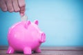 Saving, male hand putting a coin into piggy bank Royalty Free Stock Photo