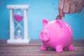 Saving, male hand putting a coin into piggy bank Royalty Free Stock Photo