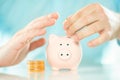 Saving money. Accounting, business, budget and finance concept. Male hands putting coin into the piggy bank near coins stack Royalty Free Stock Photo