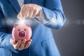 Saving money. Businesman holding pink piggy and putting coin into piggy bank