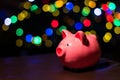 Saving money for Christmas present. Holiday piggy bank with colourful bokeh balls in the background