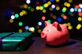 Saving money for Christmas present. Holiday piggy bank with colourful bokeh balls in the background