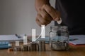 saving money concept. businessman hand holding coins and putting in jug glass using smartphone and calculator to calculate. Money Royalty Free Stock Photo